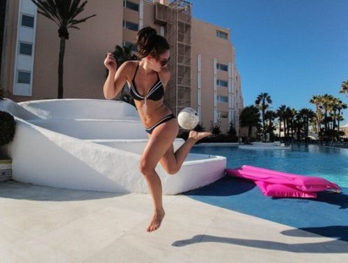 girl in bikini playing football